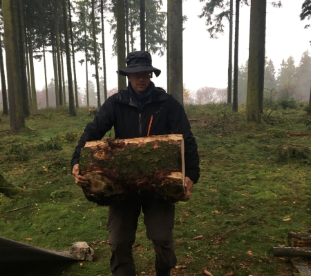 Sauerlandmodul in der Natuertrainerausbildung. Teamleiter Manuel trägt einen Baumstamm